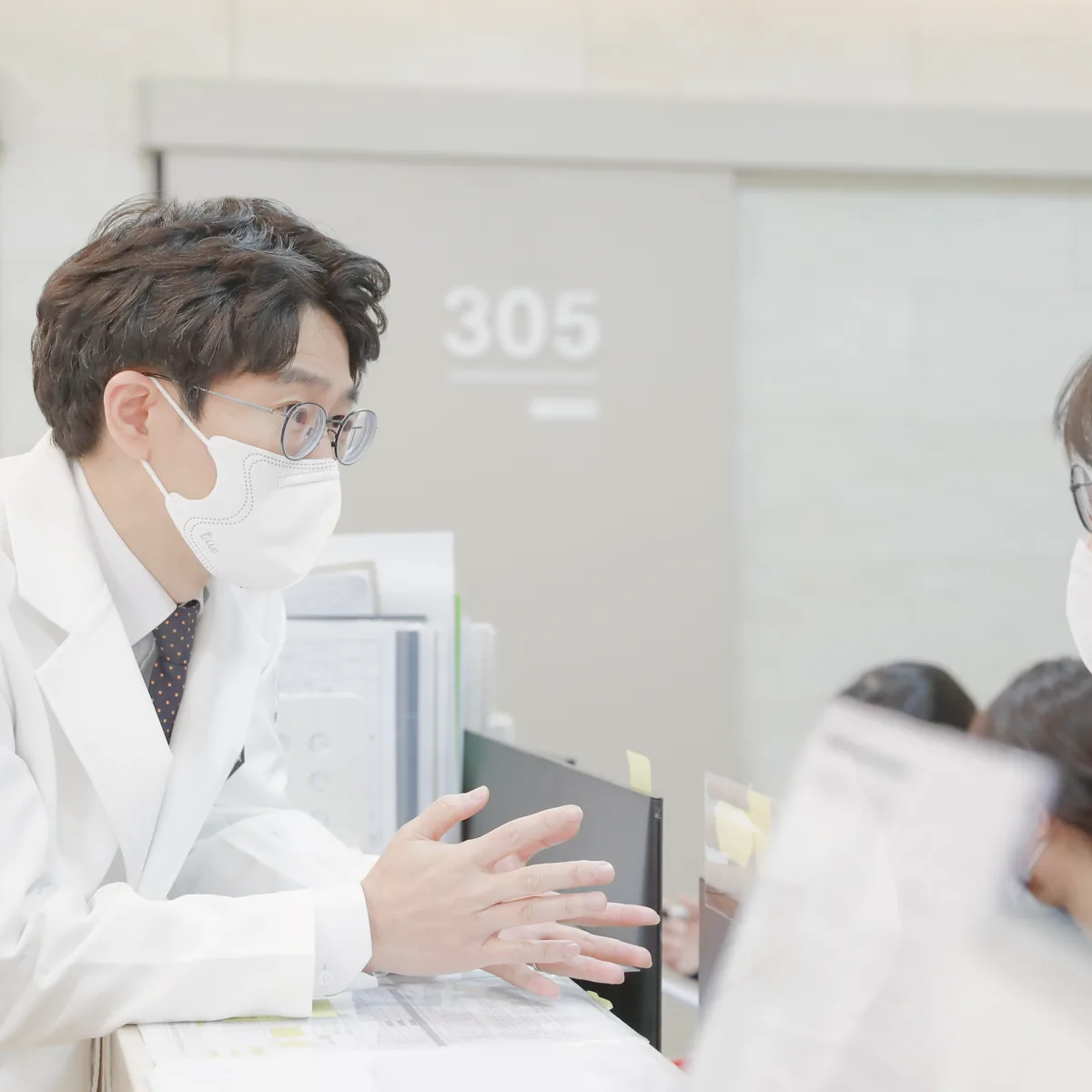 간호사실 앞에서 원장이 보호자에게 앞으로의 검사 일정과 집에서 살필 점을 설명하는 모습