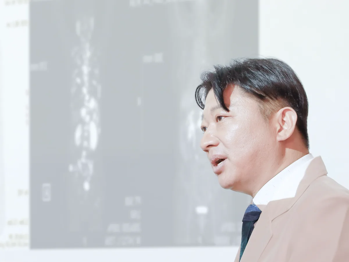 원장이 화면에 띄운 뼈 스캔 영상을 가리키며 척추와 골반 부위의 소견을 설명하는 장면