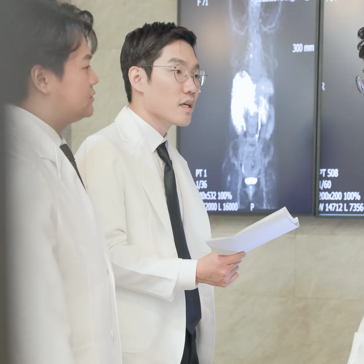 의료진이 영상 검사 화면 앞에서 결과지를 들고 다음 확인 사항을 두고 의견을 나누는 모습