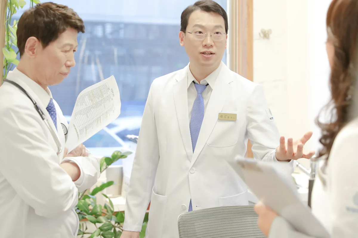 병동 복도에서 두 의료진이 서류를 들고 입원 환자의 치료 일정과 식사 계획을 상의하는 모습