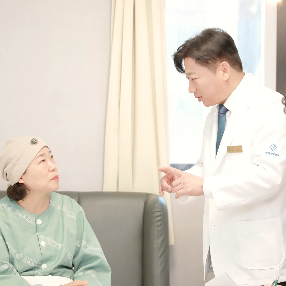 의료진이 환자와 마주 앉아 항암치료 후 남은 증상과 회복 상황을 이야기하는 장면