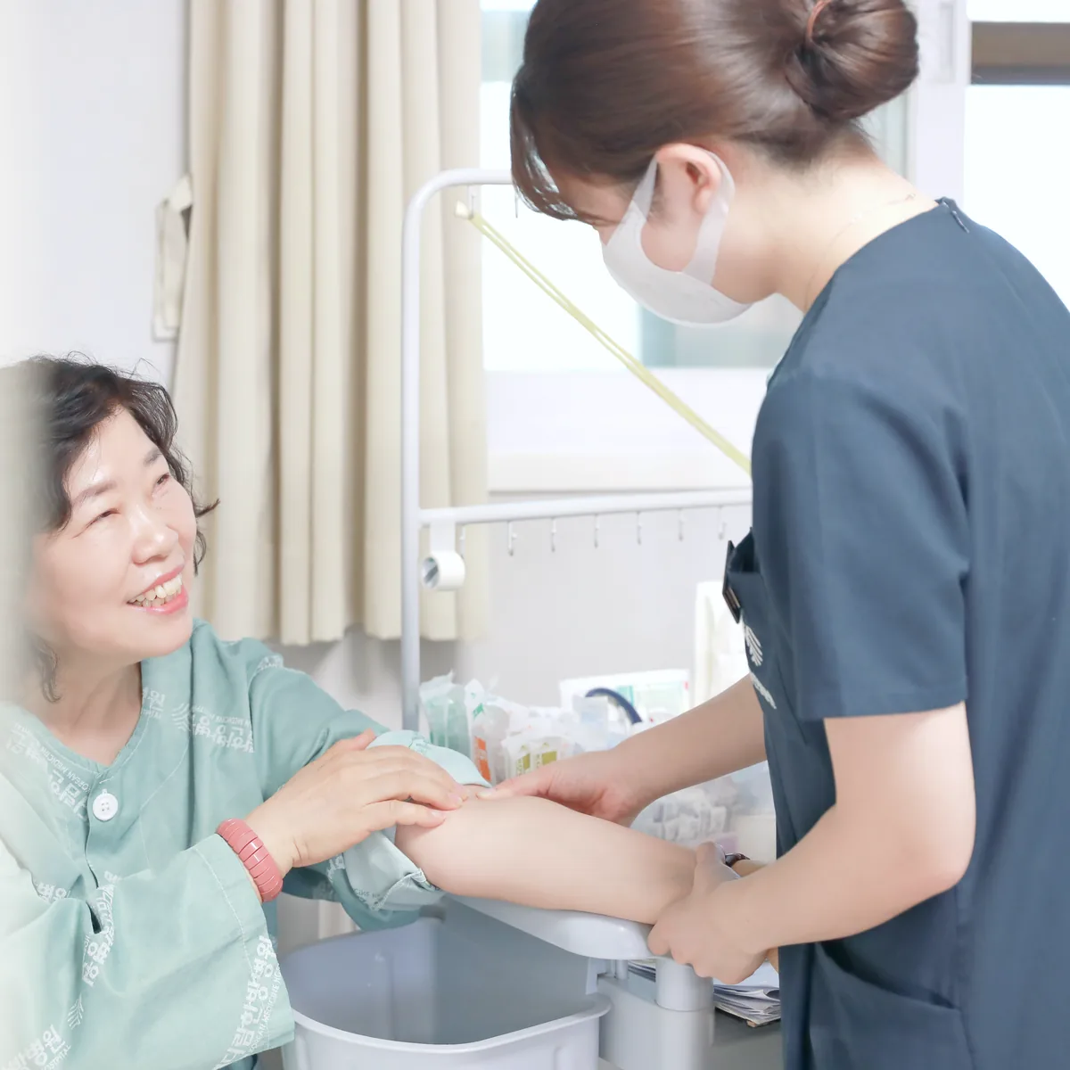 간호사가 환자의 팔 상태를 살피며 항암 후 손발 저림 증상을 확인하는 모습