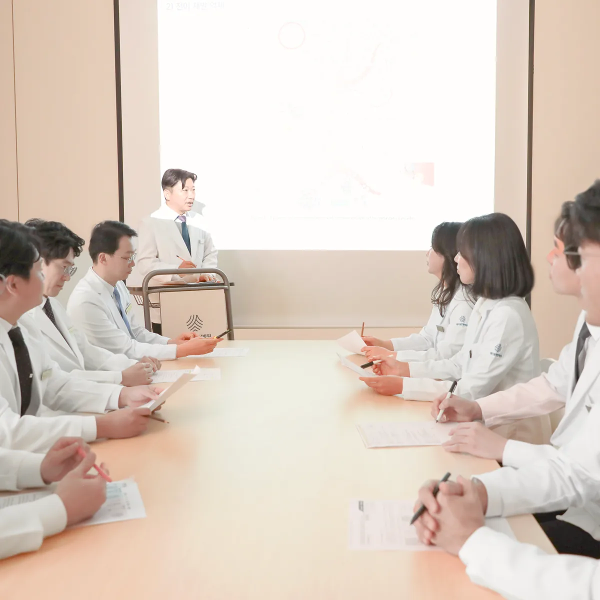 의료진이 회의실에 모여 암 전이와 재발에 관한 자료를 함께 검토하는 장면