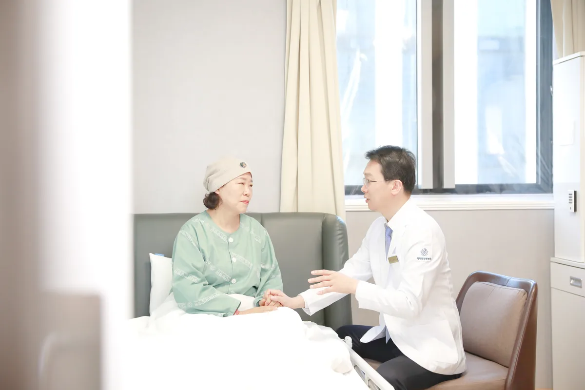 의료진이 병실에서 환자분의 손을 잡고 회복 상태를 살피며 이야기를 나누는 모습