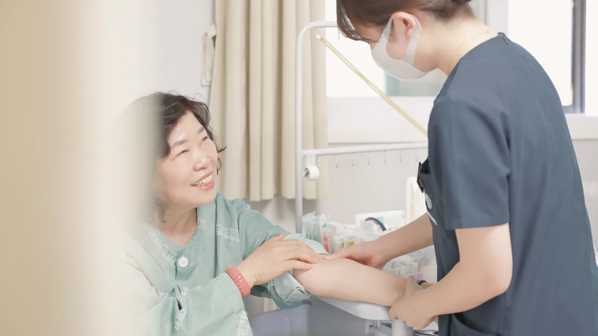 입원 환자가 팔을 내밀자 간호사가 빈혈과 영양 상태를 확인하기 위한 처치를 준비하는 모습