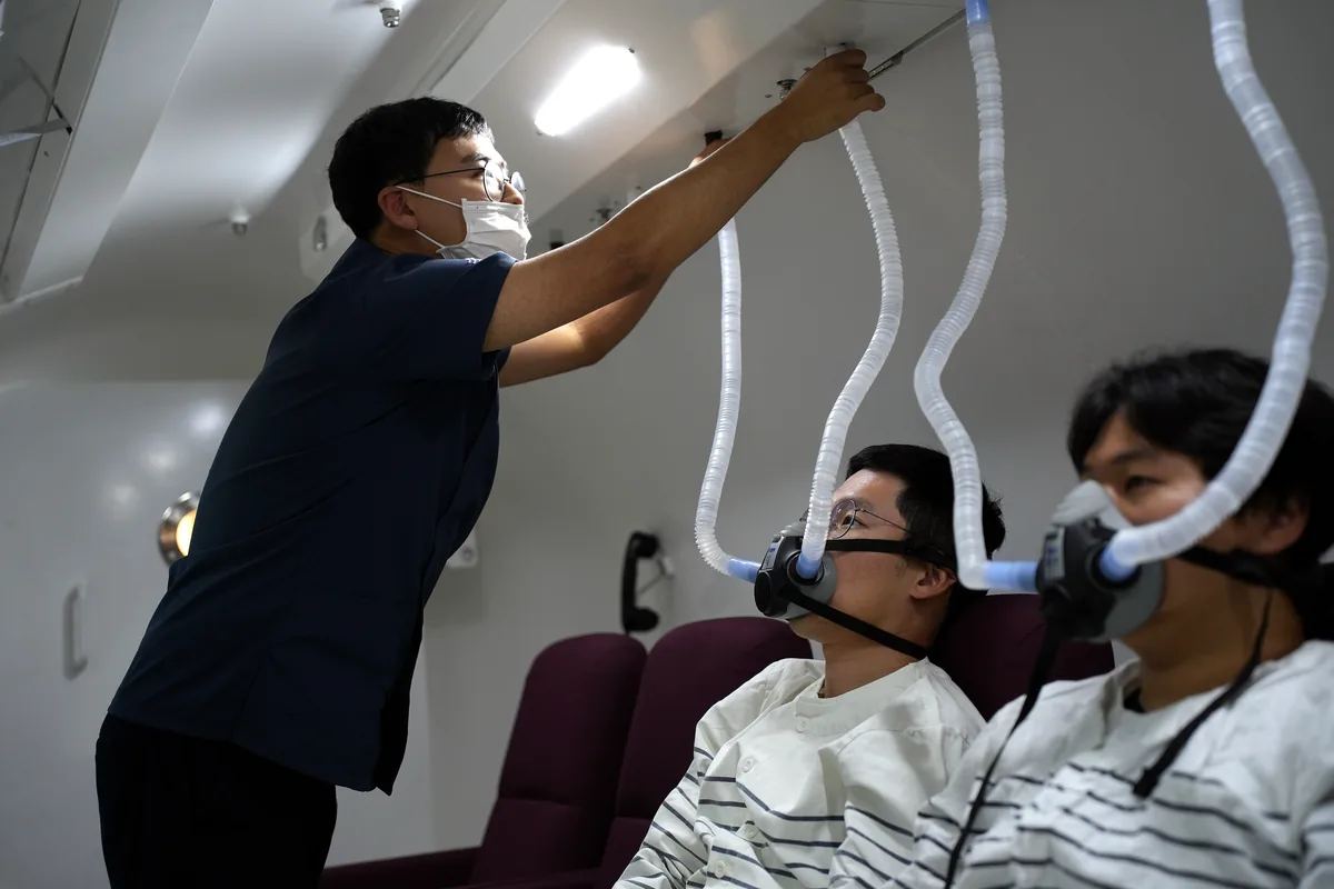 고압산소챔버 안에서 의료진이 환자의 산소 마스크 착용 상태를 확인하는 모습