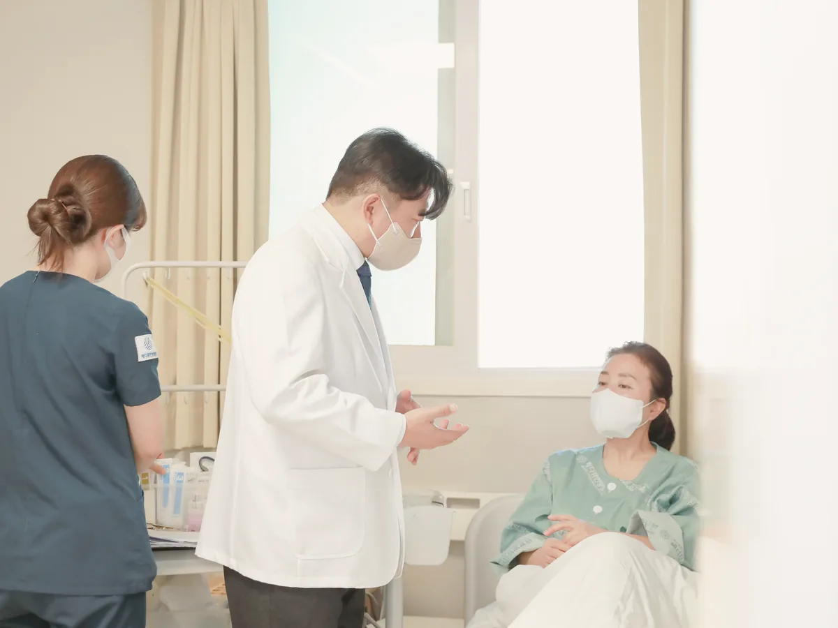 원장이 병상 옆에서 수술을 앞둔 환자와 간 기능 검사 결과를 이야기하는 모습