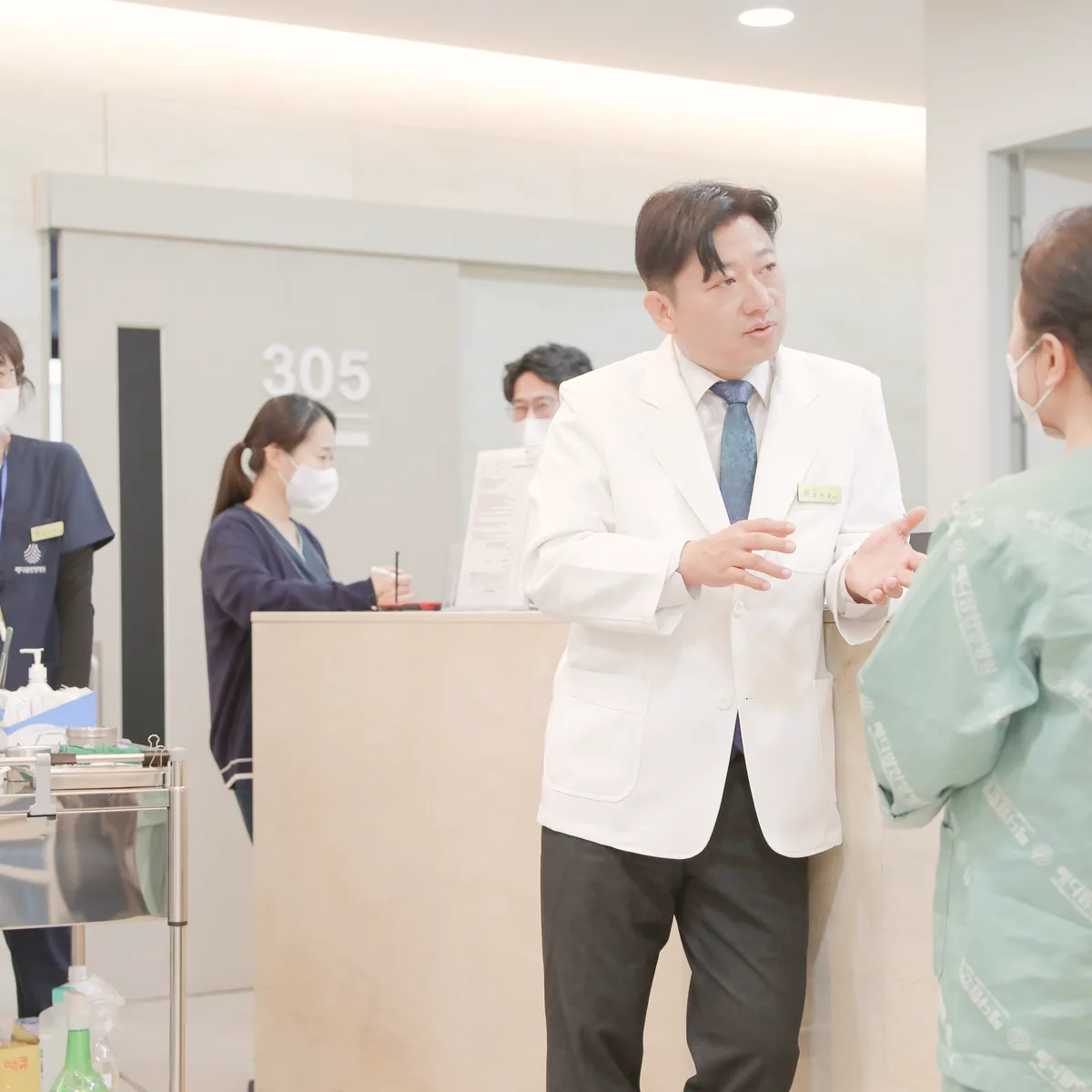 원장이 병동 간호사실 앞에서 수술 후 회복 일정과 식사 진행을 설명하는 모습