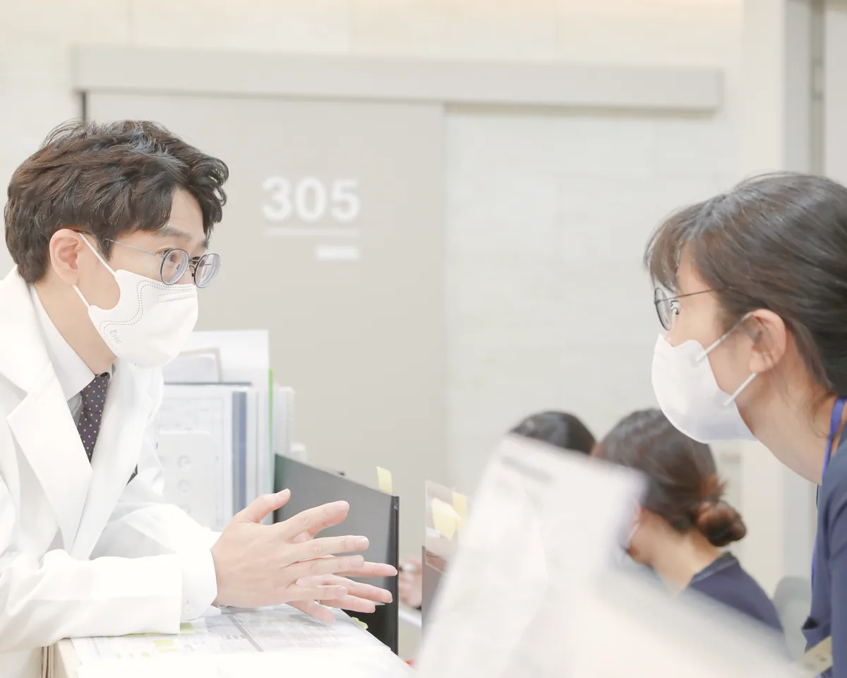 간호사실 앞에서 원장이 간호사와 다음 검사 일정과 환자 상태를 상의하는 모습