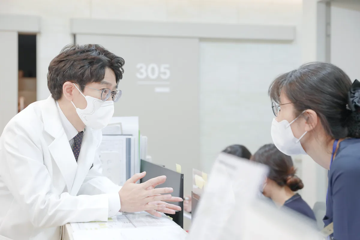 병실 앞에서 원장이 마스크를 쓴 보호자에게 검사 결과와 앞으로의 치료 순서를 설명하는 모습