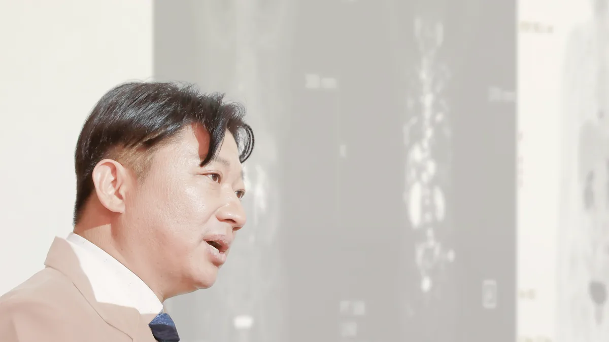 원장이 뼈 스캔 영상 앞에서 전이 부위와 치료 방향을 설명하는 모습