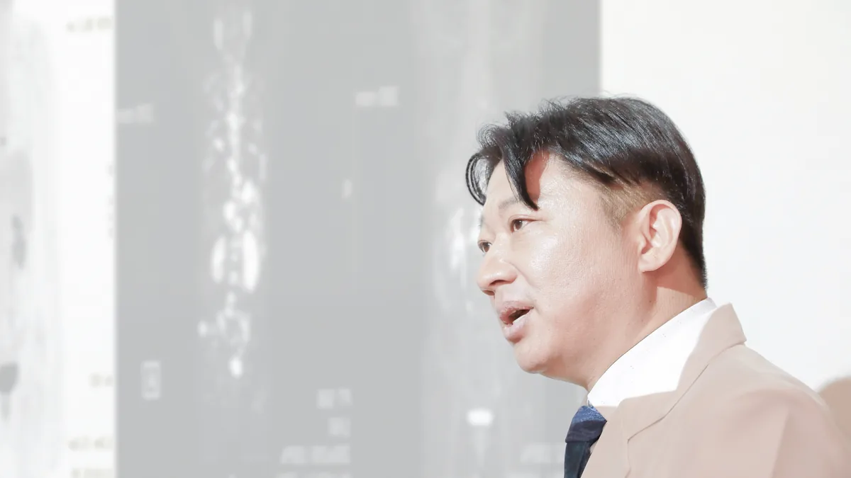 뼈 스캔 영상이 띄워진 화면 앞에서 원장이 전신 뼈 사진을 가리키며 설명하는 모습