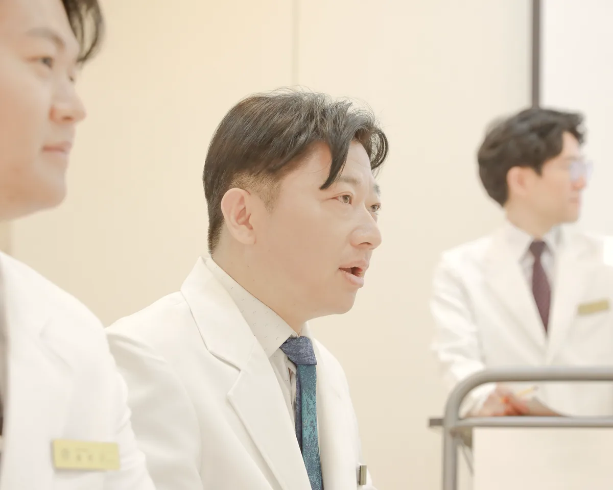 흰 가운을 입은 원장들이 나란히 앉아 입원 환자의 검사 결과와 관리 계획을 의논하는 모습