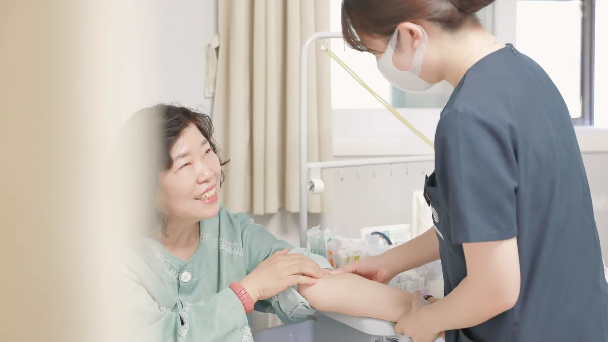 메디람한방병원 병실에서 간호사가 환자에게 정맥주사를 놓으며 상태를 확인하는 모습