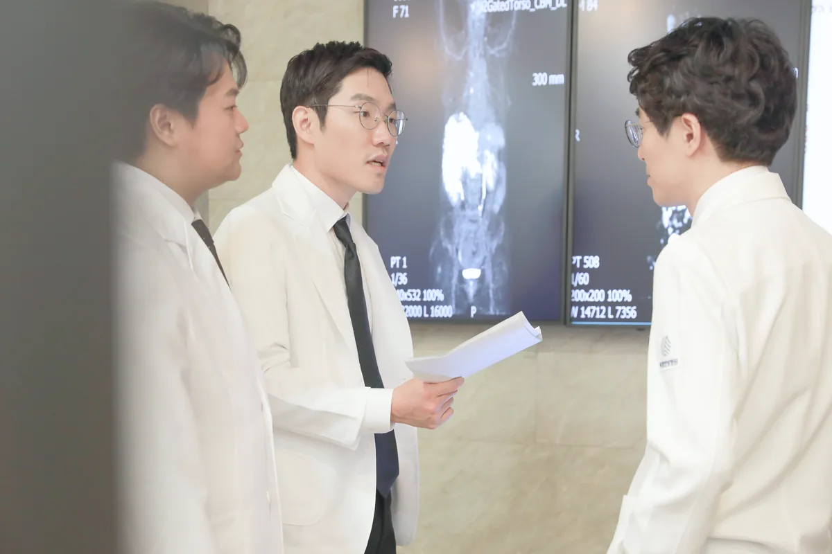 의료진 세 명이 영상 판독 화면 앞에서 서류를 보며 추적 검사 결과를 함께 확인하는 모습